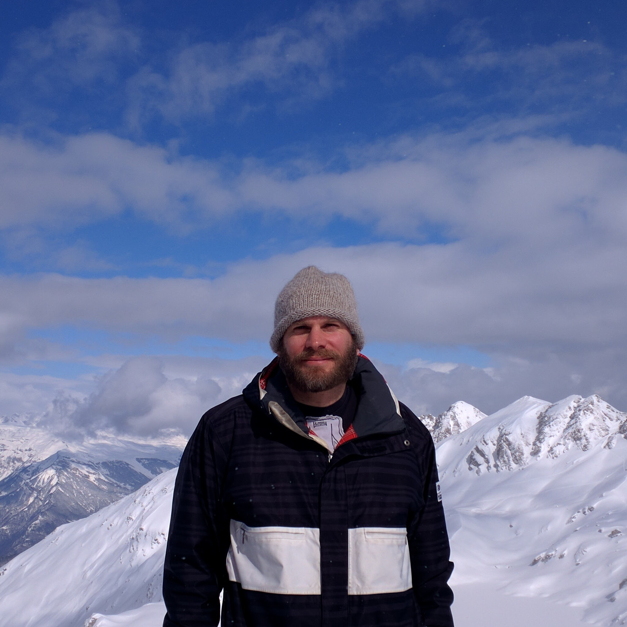 The artist stands in front of a white glacier, crisp blue sky in the background.